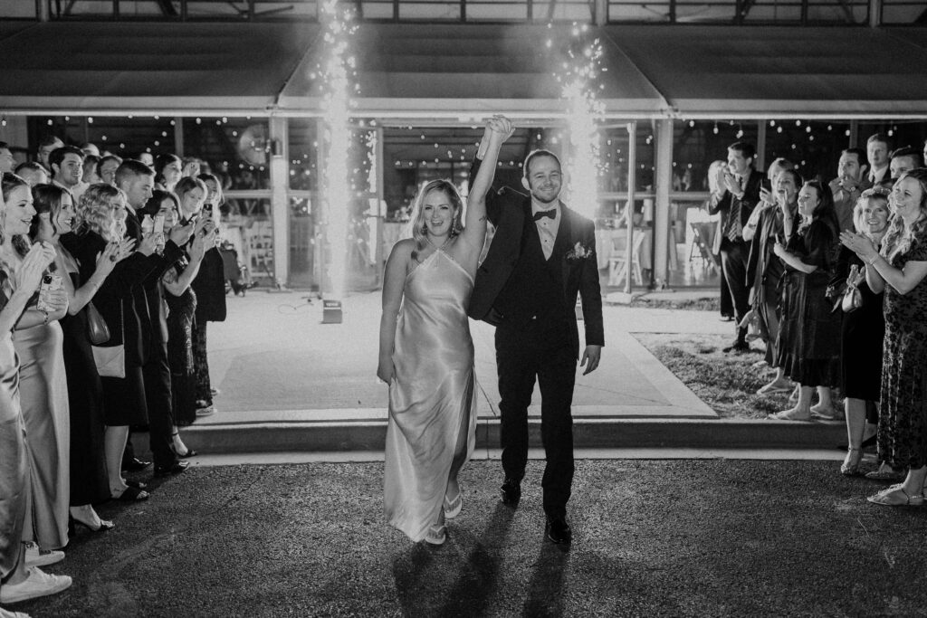 Bride and groom exiting their wedding with fireworks behind them.