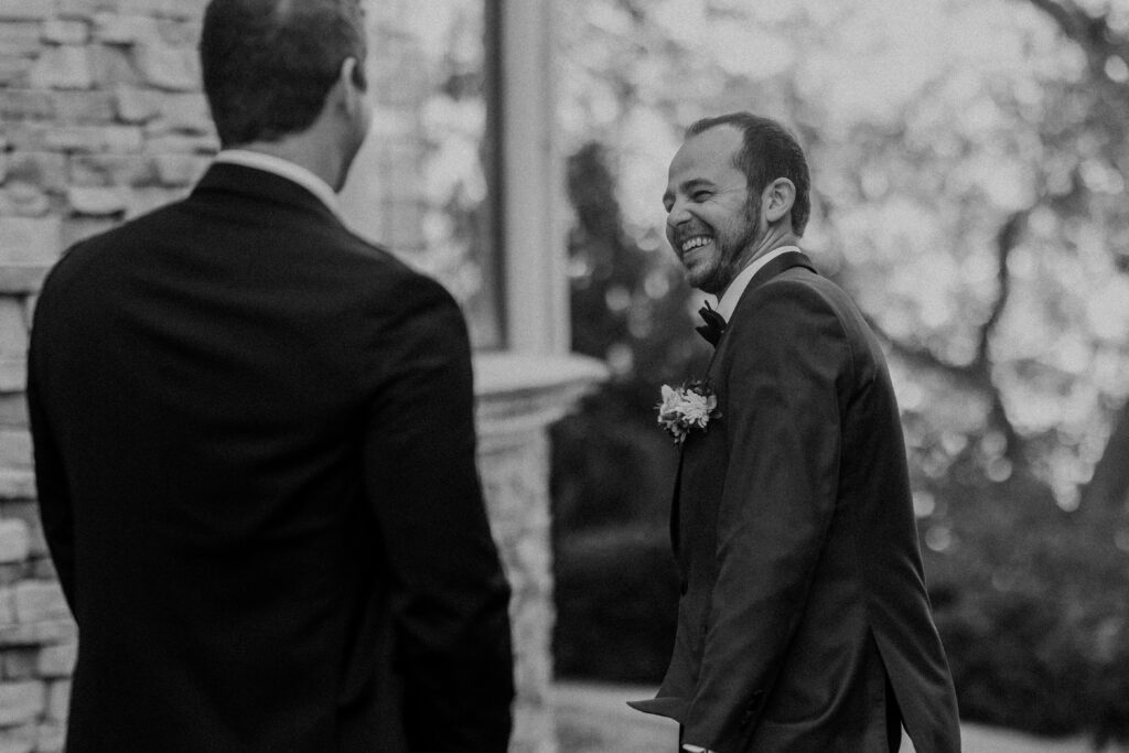 Groom and best man laughing during their first look.