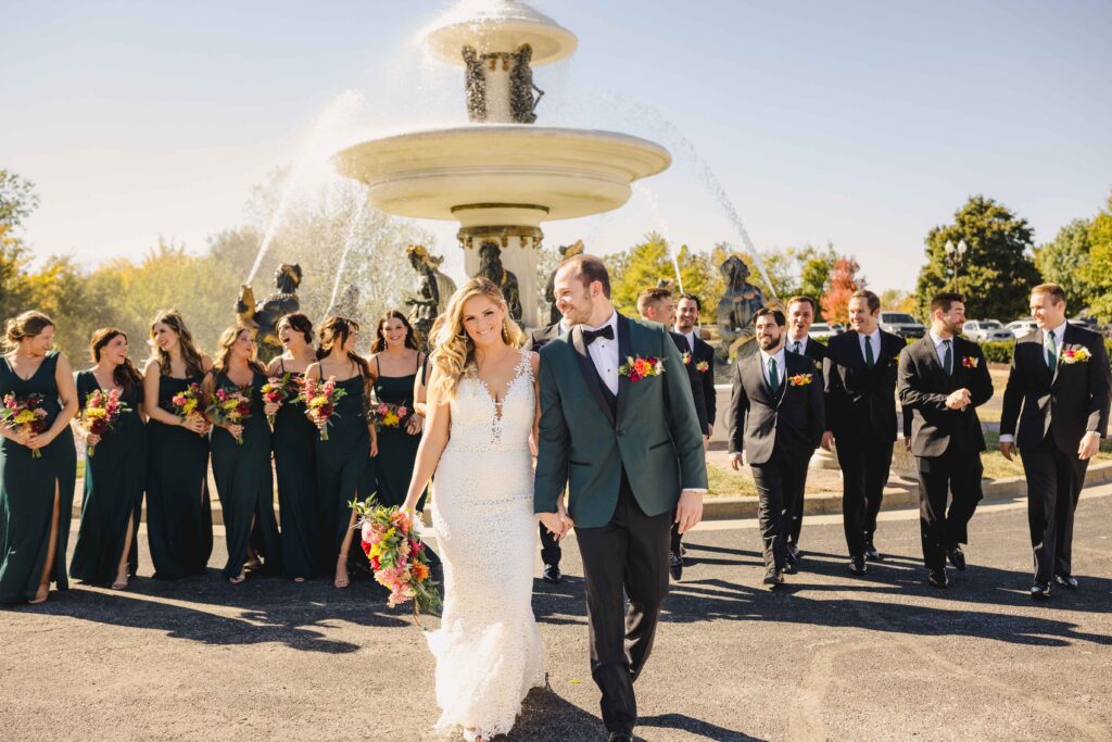 Kansas City Wedding Photographer photoshoot with the newlywed couple walking with their bridal party following behind, smiling and laughing. 