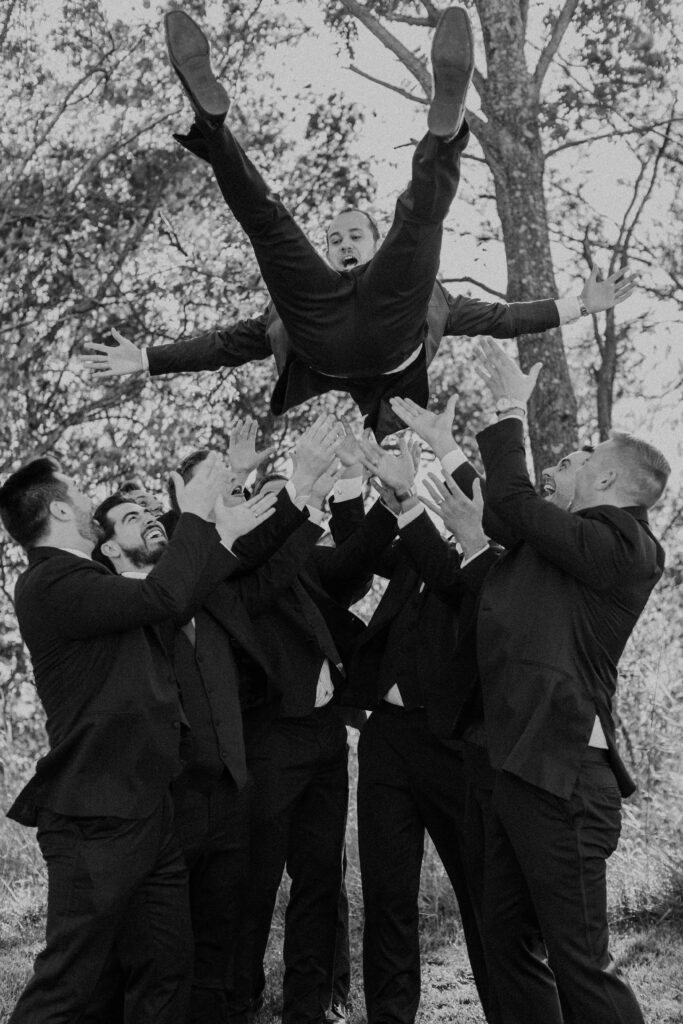 Groomsmen throwing the groom up into the air.