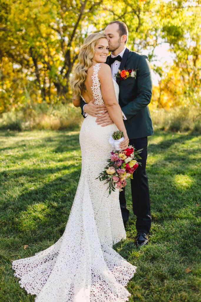 Groom kissing the bride on the head during their wedding photoshoot at Avent Orangery Wedding Venue taken by their Kansas City Wedding Photographer.