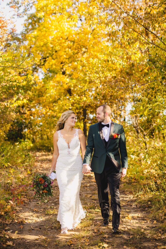 Bride and groom walking through the fall leaves at Avent Orangery in Kansas City.