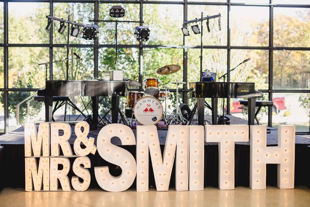 A large light-up sign that says "Mr. and Mrs. Smith" at a wedding reception.