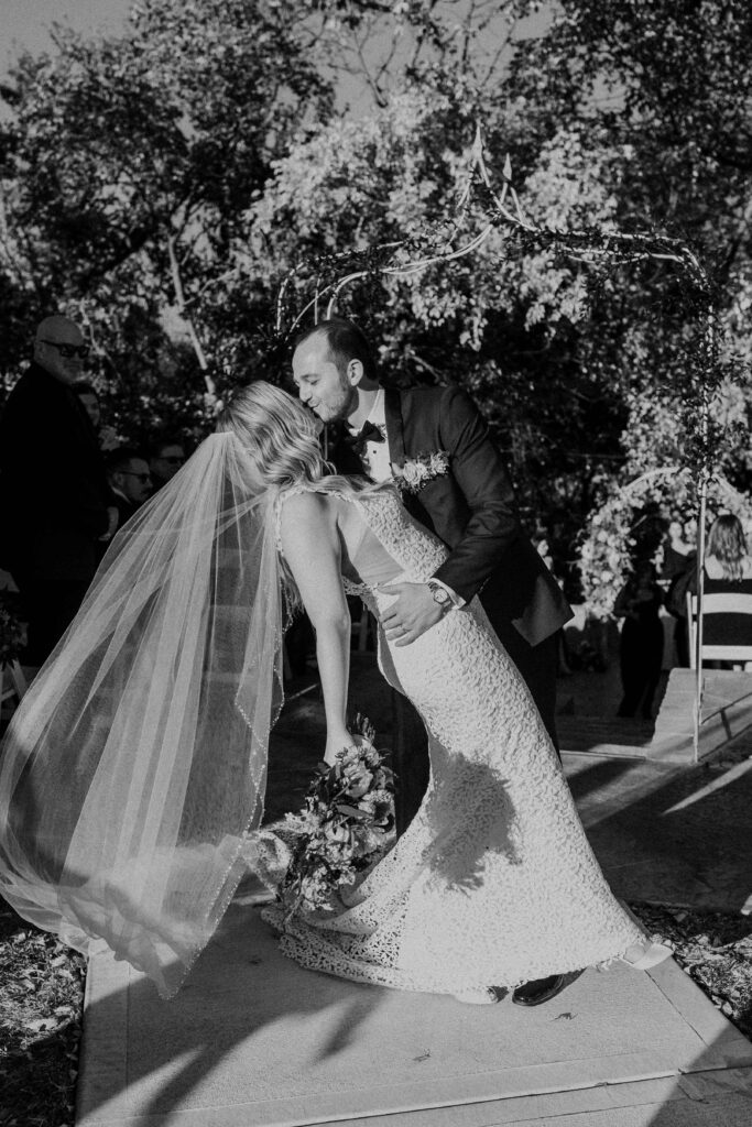 Groom dipping his wife in for a kiss at the end of the aisle. 