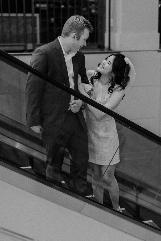 A couple posing on an escalator for their engagement photoshoot.