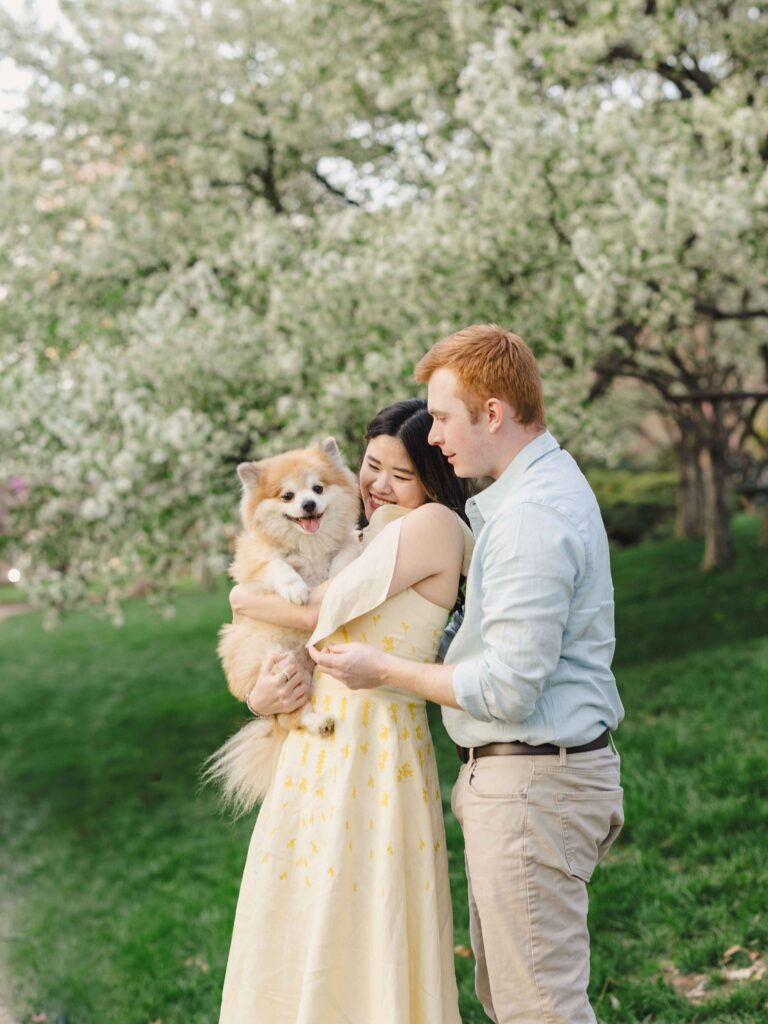 Couple hugging their dog in a park.