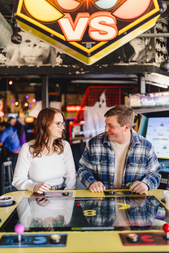 A couple playing a game at their engagement photoshoot at an arcade in Kansas City.