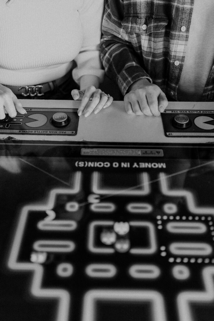 A close up of a couple playing a game at an arcade.