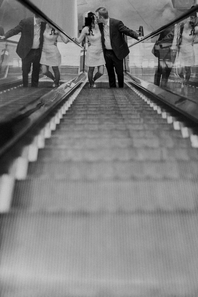 A couple kissing on an escalator. 