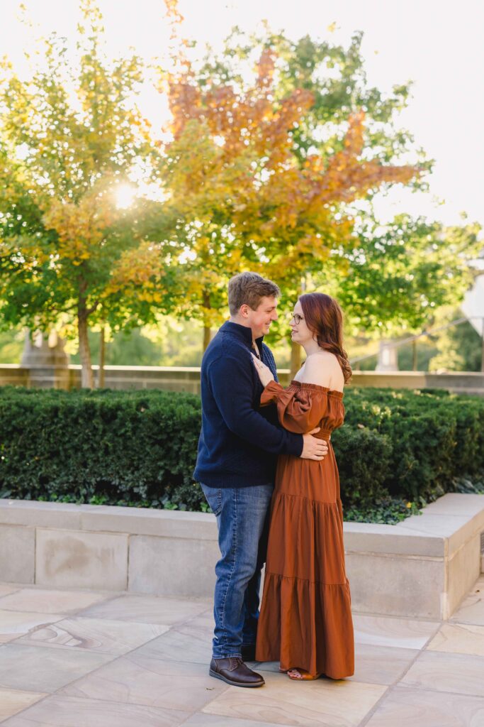 Engagement photoshoot of a couple in a park looking at each other romantically. 