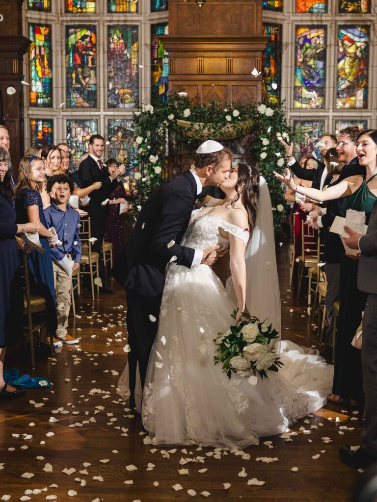 Bride and groom kissing at the end of the aisle after being pronounced husband and wife.