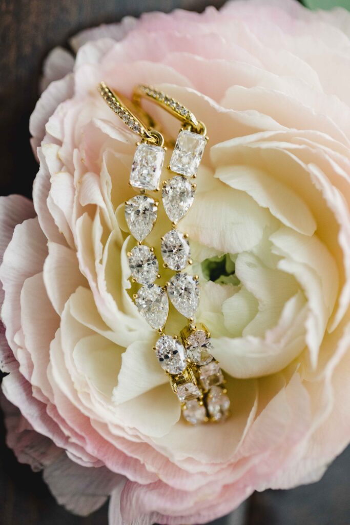 Brides's gold diamond earrings on a flower. 