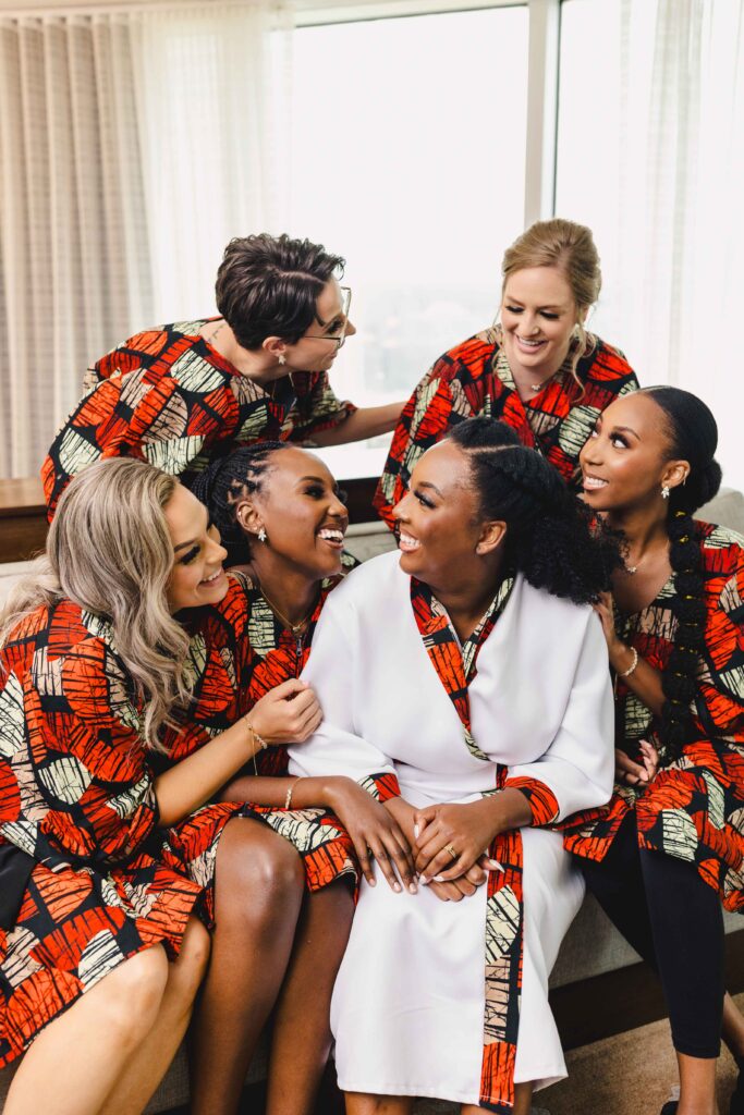 Bride and bridesmaids smiling in their robes before the wedding. 