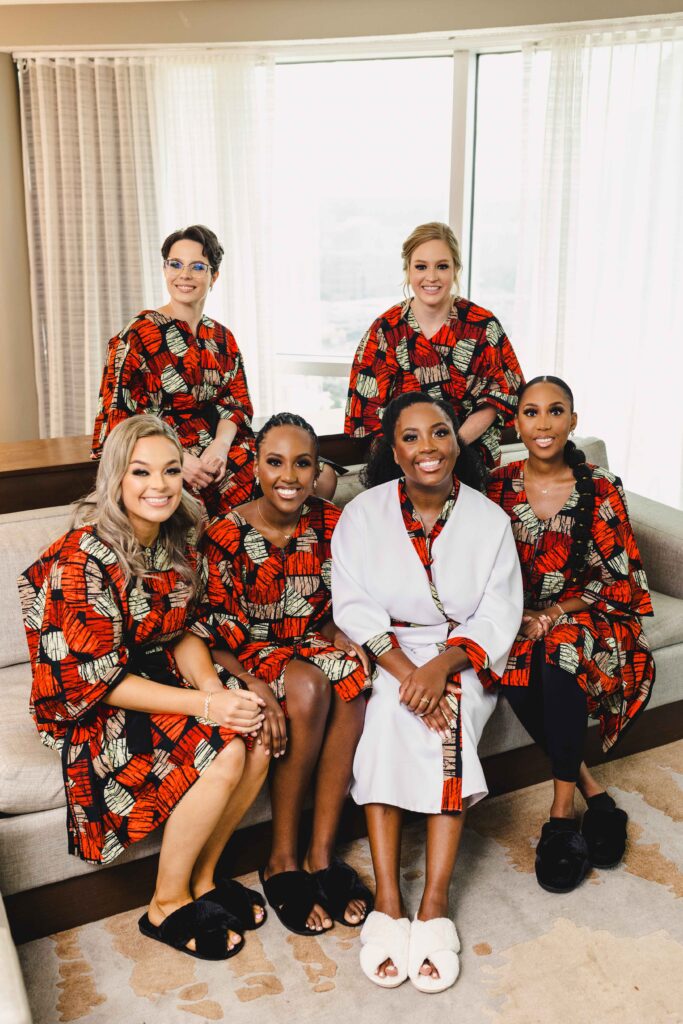 Bride and bridesmaids sitting on a couch in their getting ready robes. 