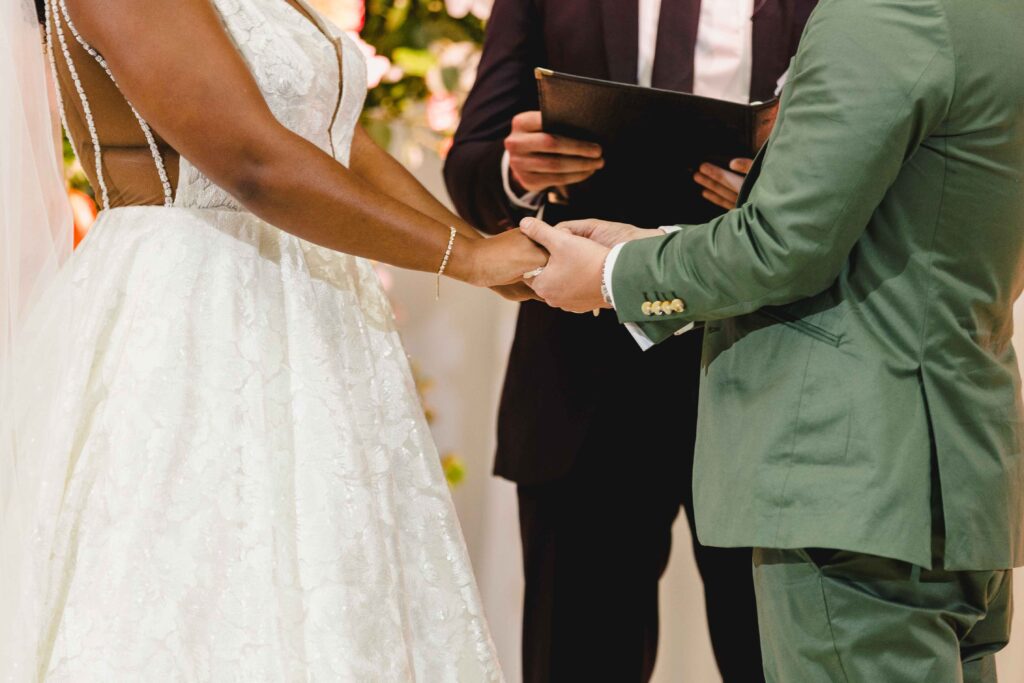 Close up of the bride and groom holding hands during their Nelson Atkins wedding ceremony.