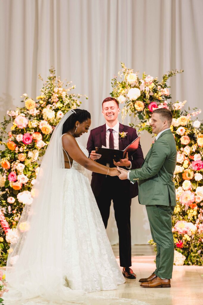 Bride, groom, and officiant laughing during the wedding ceremony. 