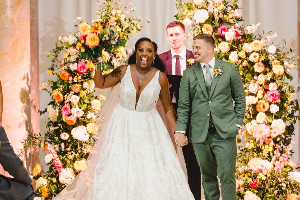 Bride and groom cheering before walking down the aisle after saying "I do"