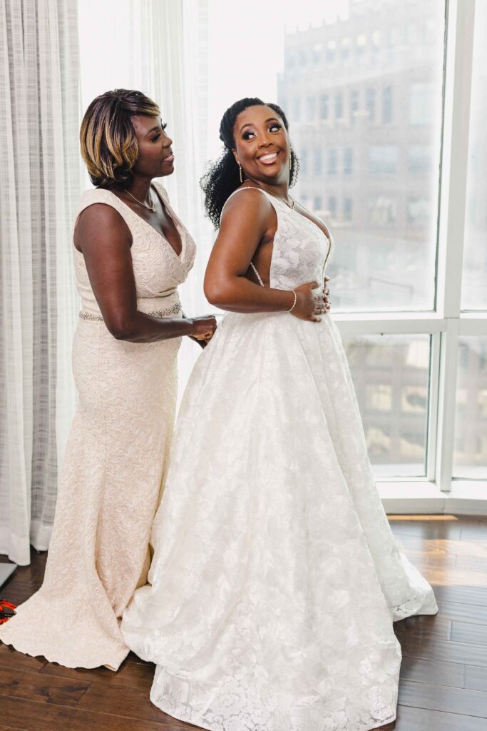 The brides mother helping her button her wedding dress.