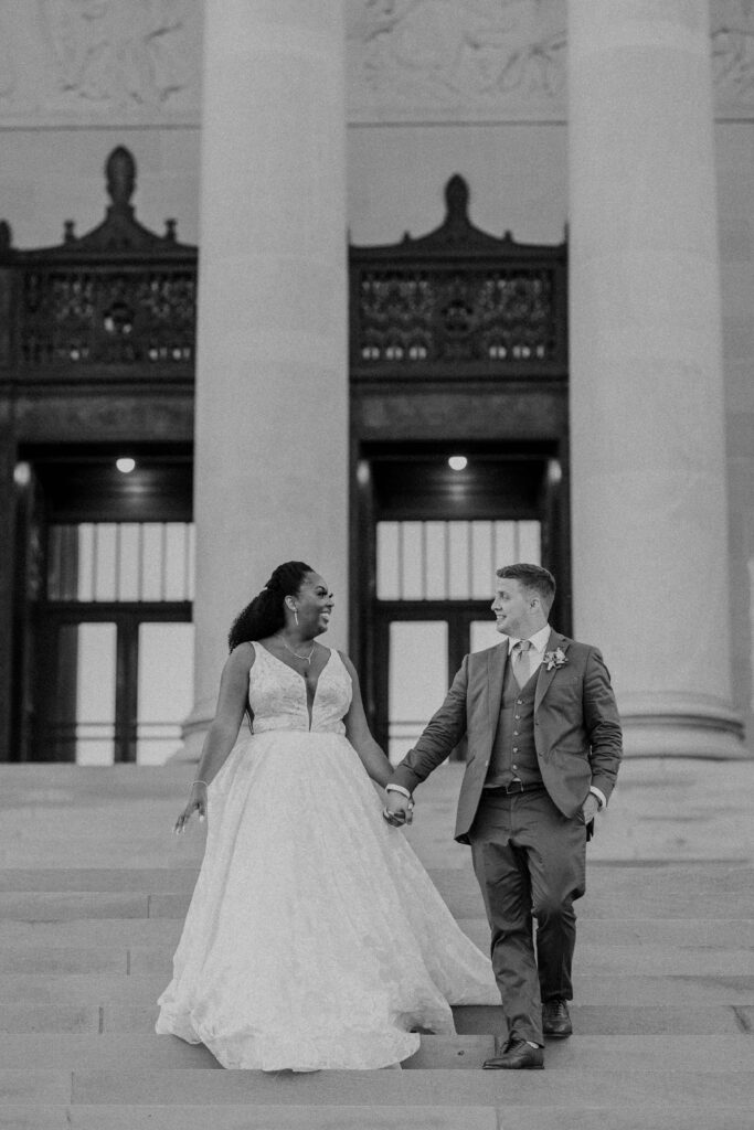 Newlyweds walking hand in hand down the steps of their Nelson Atkins wedding.