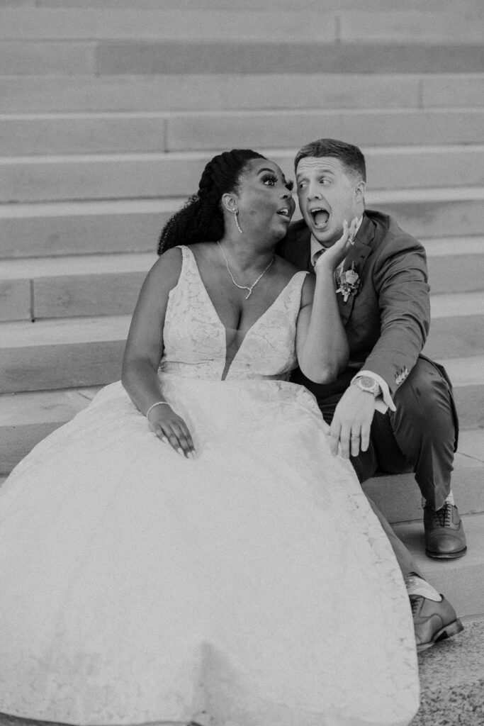 Newlyweds doing a silly face while sitting on the steps of their Kansas City MO Wedding Venue.