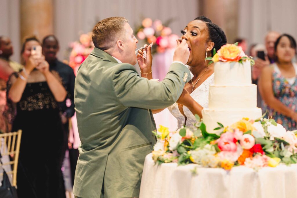 Bride and groom feeding each other wedding cake. 