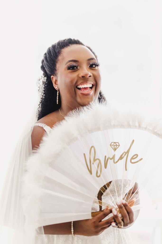 Bride holding a feathered fan that says "Bride" 