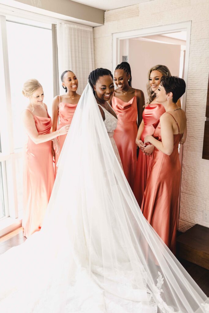 Bridesmaids smiling at the bride as they see her in her dress for the first time. 