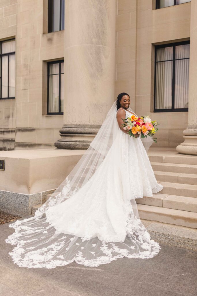 Bride holding her bridal bouquet and posing on the steps of their Nelson Atkins wedding.