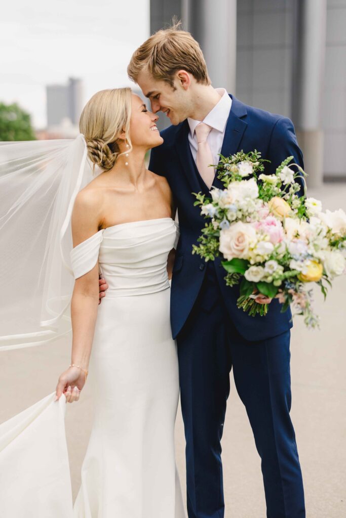 Bride and Groom smiling at one another downtown before referring to their wedding family photos list.