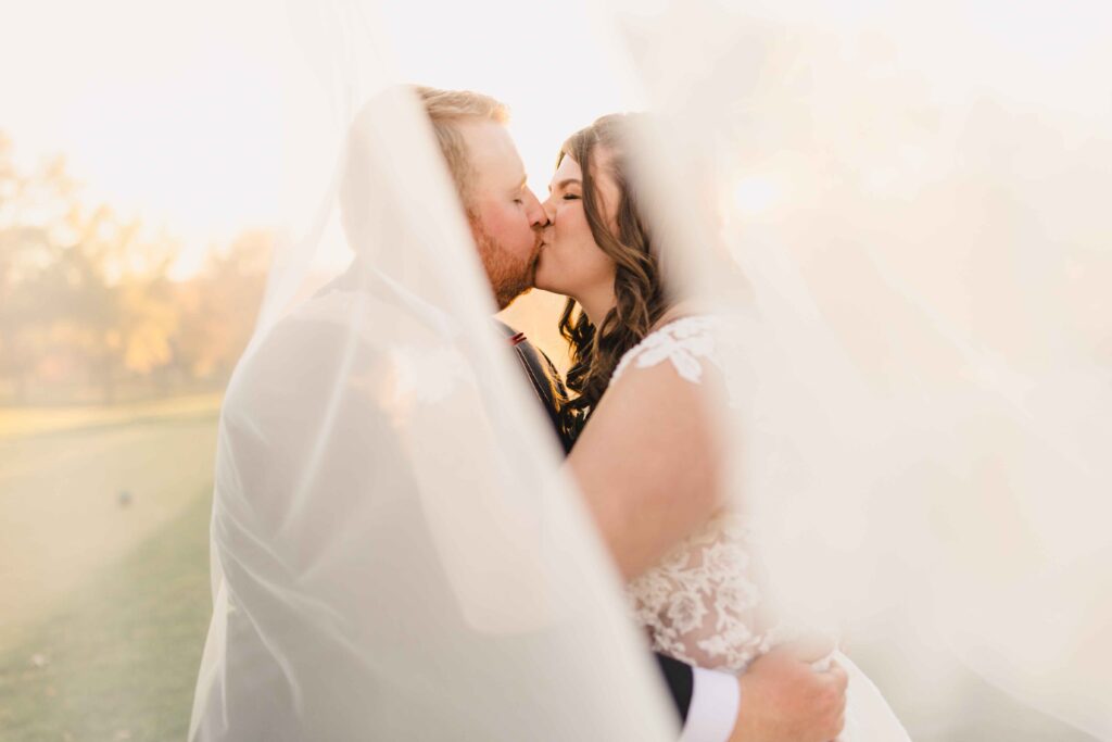 Bride and groom kissing under the bride's veil at their Oakwood Country Club wedding. 