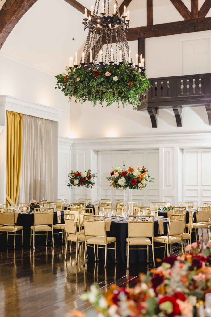 The Oakwood Country Club wedding reception decorations. The tables are filled with vibrant florals and gold accents. 