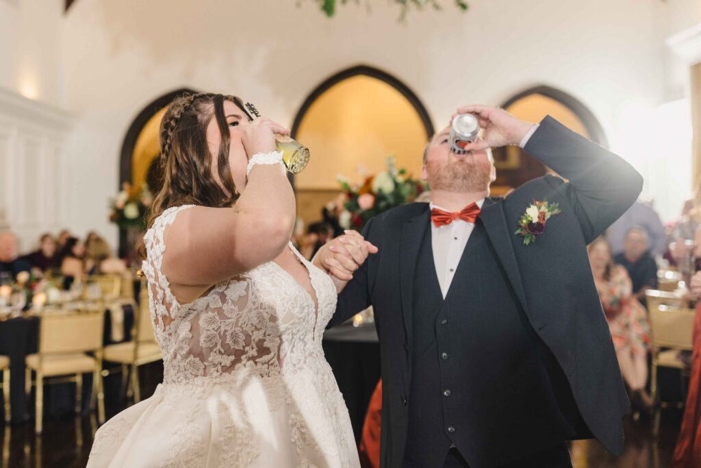 Bride and groom chugging a drink as they enter their wedding reception. 