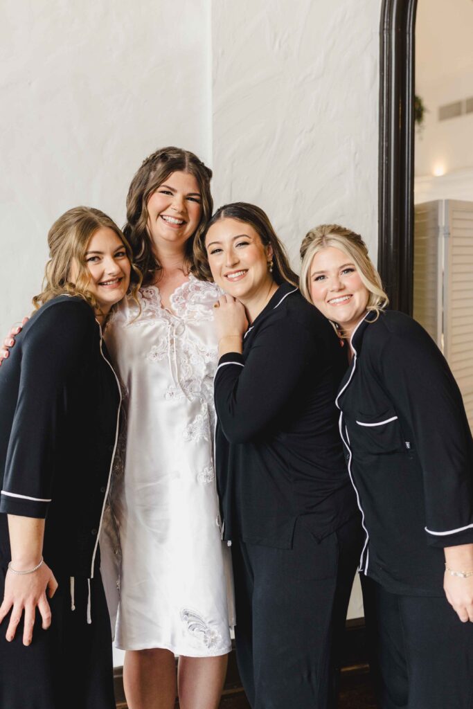 Bride and bridesmaids smiling together in pajamas. 