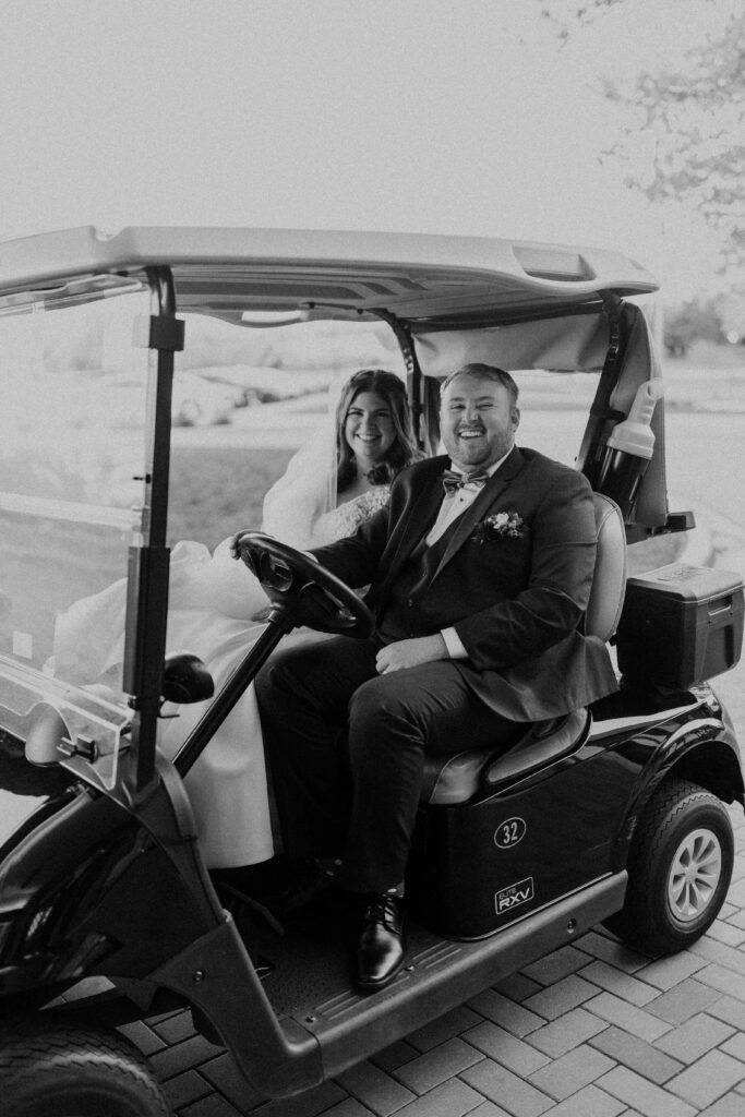 Bride and groom riding a golf cart. 