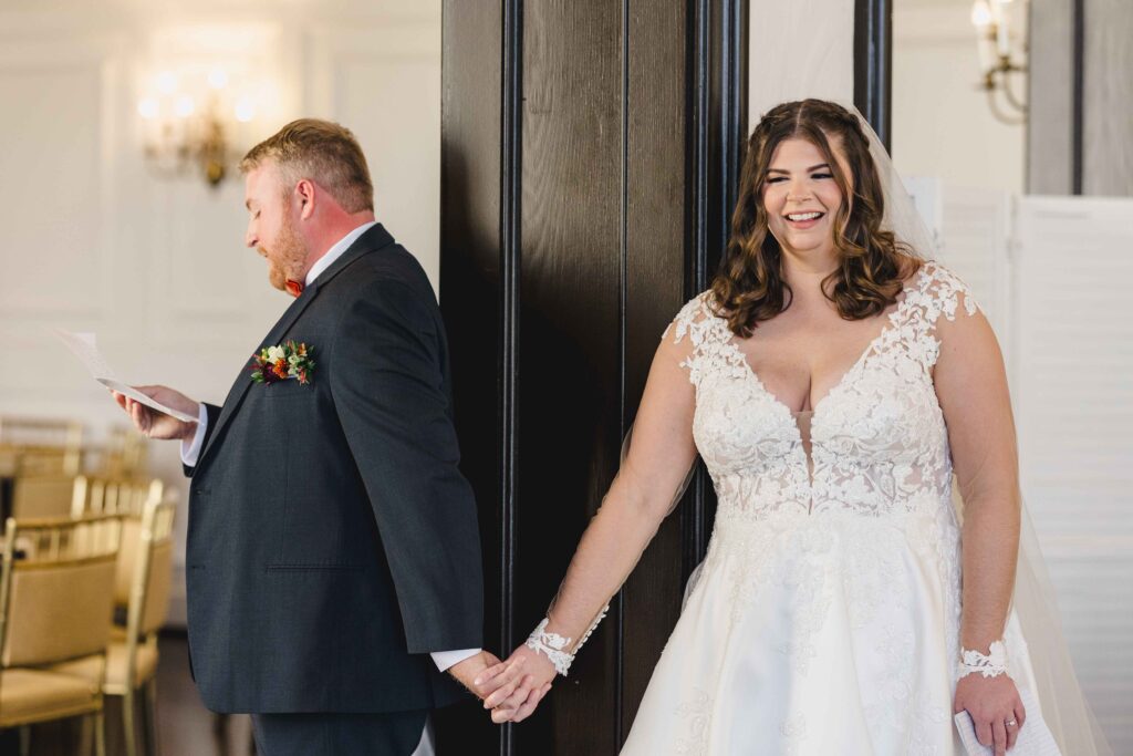 Bride and groom holding hands around a corner for an intimate letter reading. 