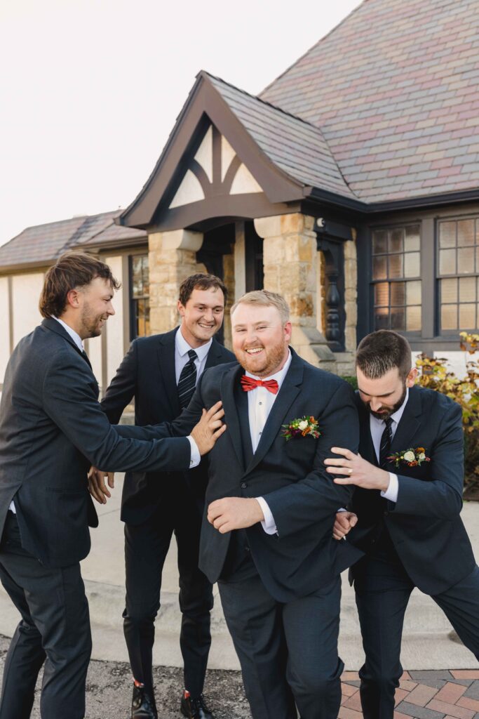 Groom and groomsmen playing around and laughing.