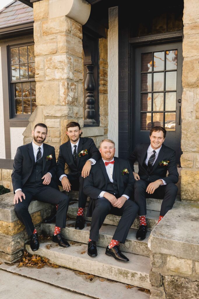 Groomsmen sitting on the steps before the Oakwood Country Club wedding ceremony. 