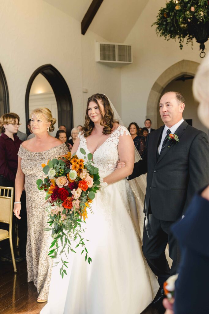 Bride walking down the aisle with her family.