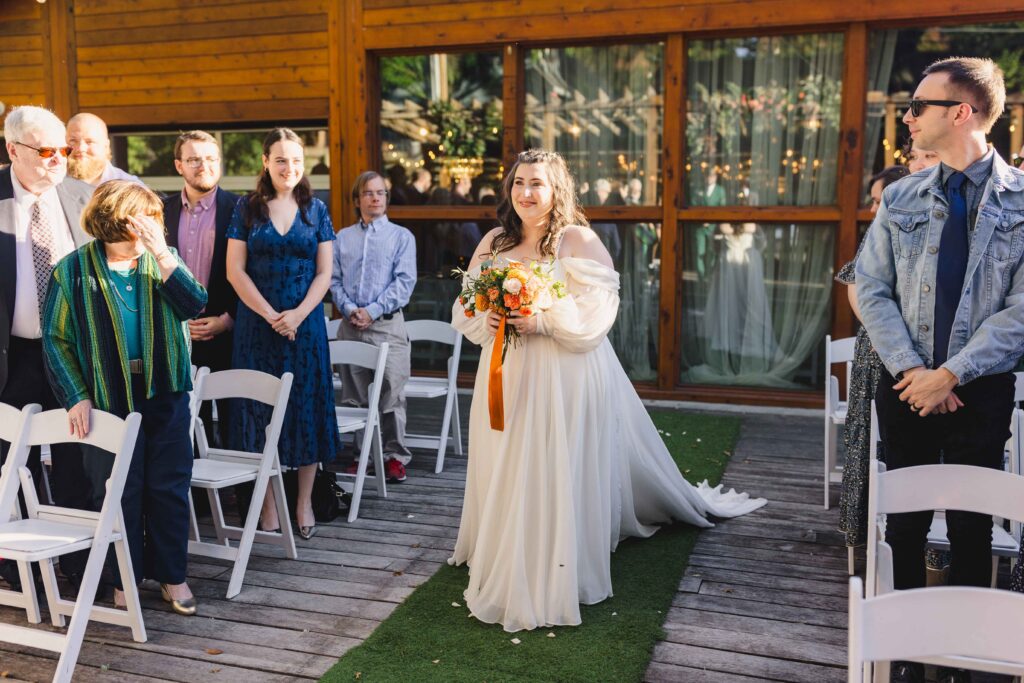 Bride walking down the aisle smiling at her groom.