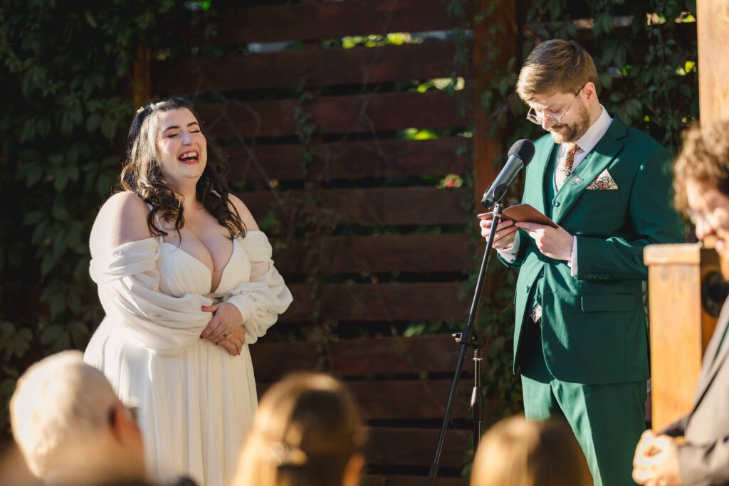 Groom giving his vows as the bride laughs. 