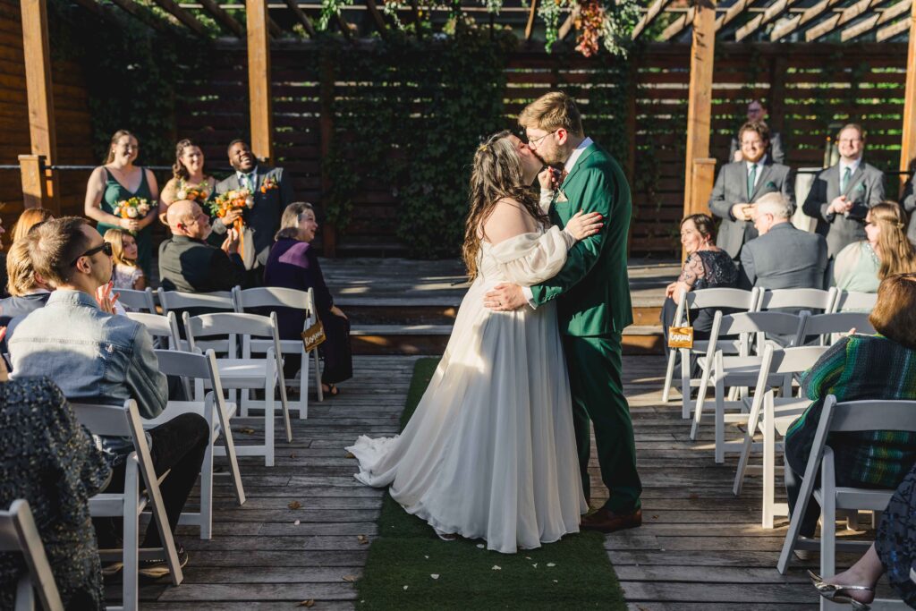 Bride and groom kissing at the end of the aisle at their wedding ceremony at The Magnolia Brookside. 