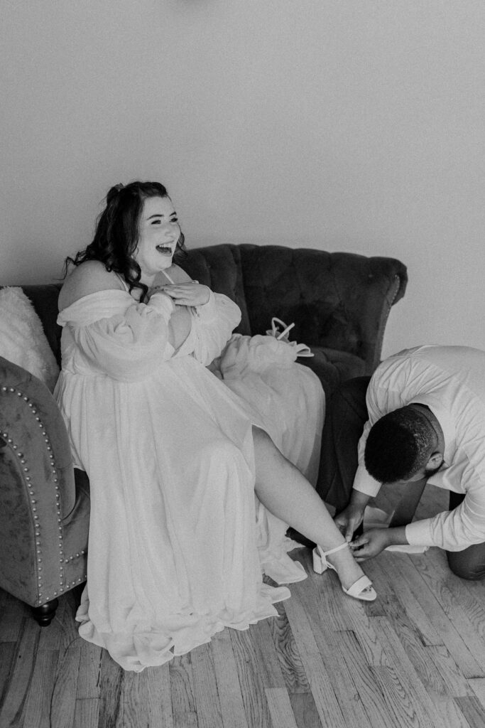 Bride's friend putting on her heels for her.