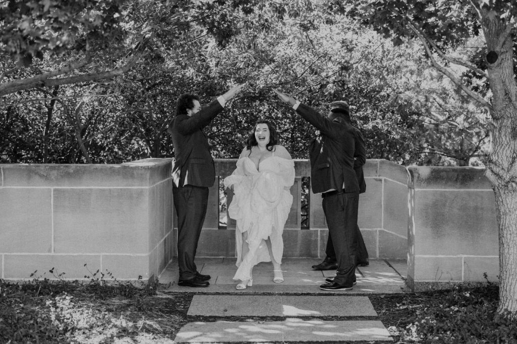 Bride laughing as the groomsmen make an arch for her. 