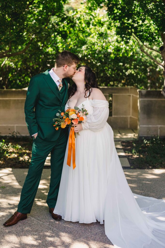 Bride and groom kissing in a garden.