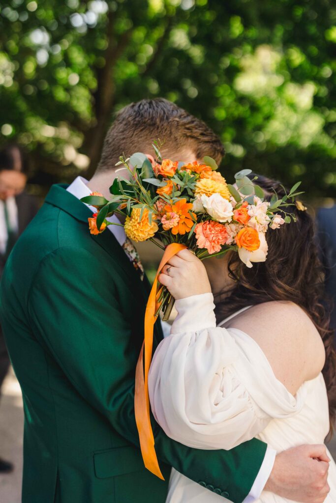 Bride and groom kissing behind the bridal bouquet. 