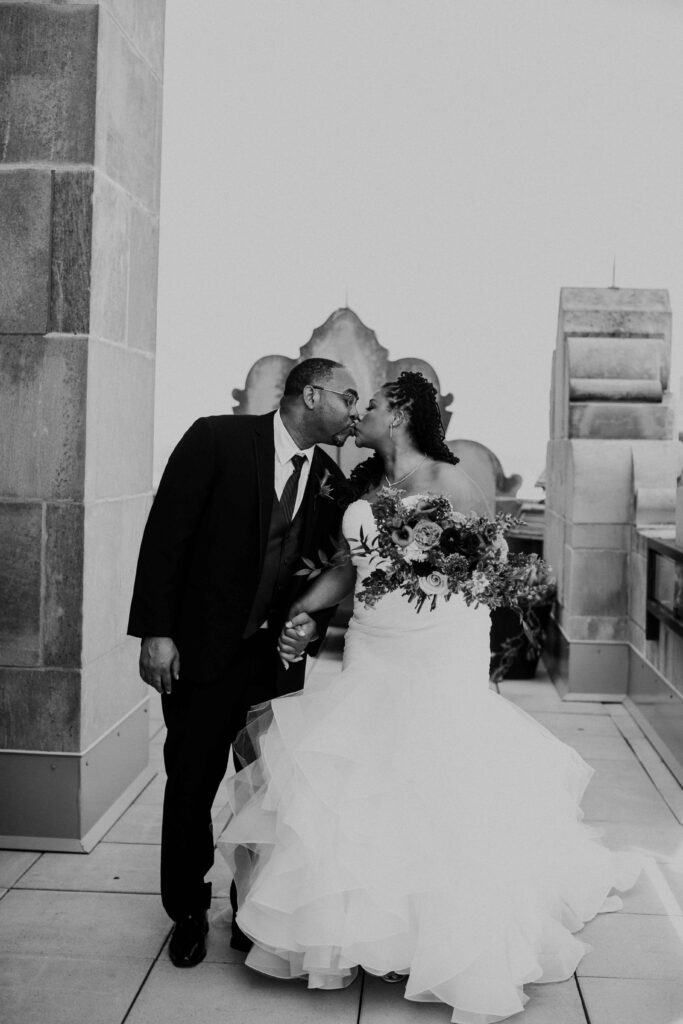 Bride and groom kissing with rooftop views in the background.
