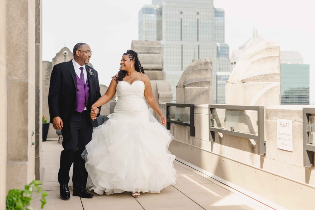 Bride and groom walking hand in hand on the rooftop of their Kansas City wedding venue.