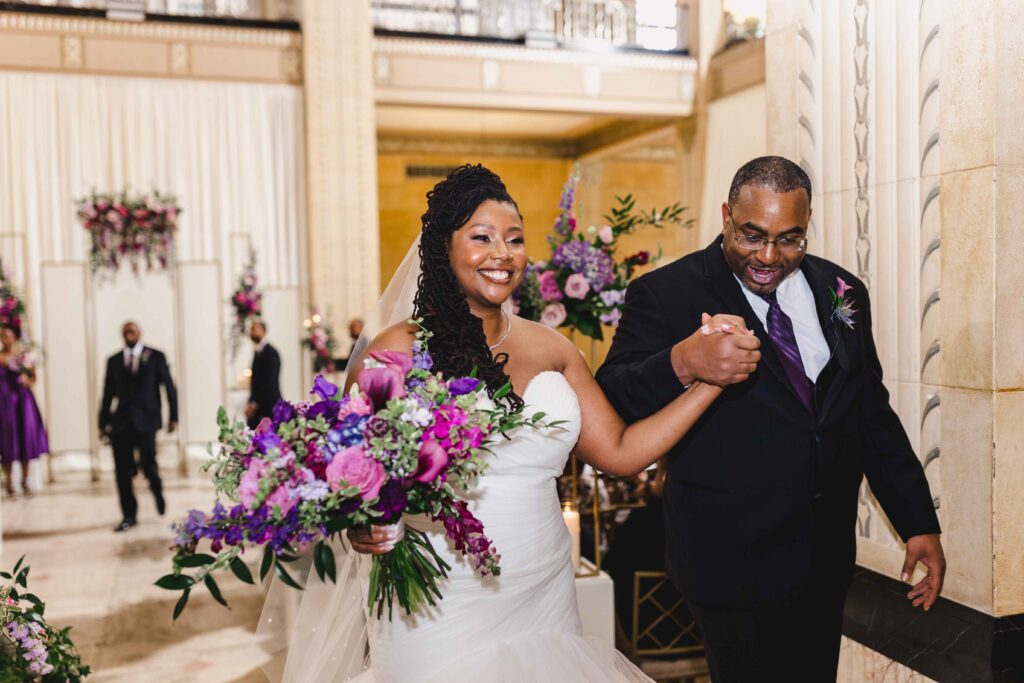 The newlyweds holding hands and smiling while leaving their wedding ceremony.