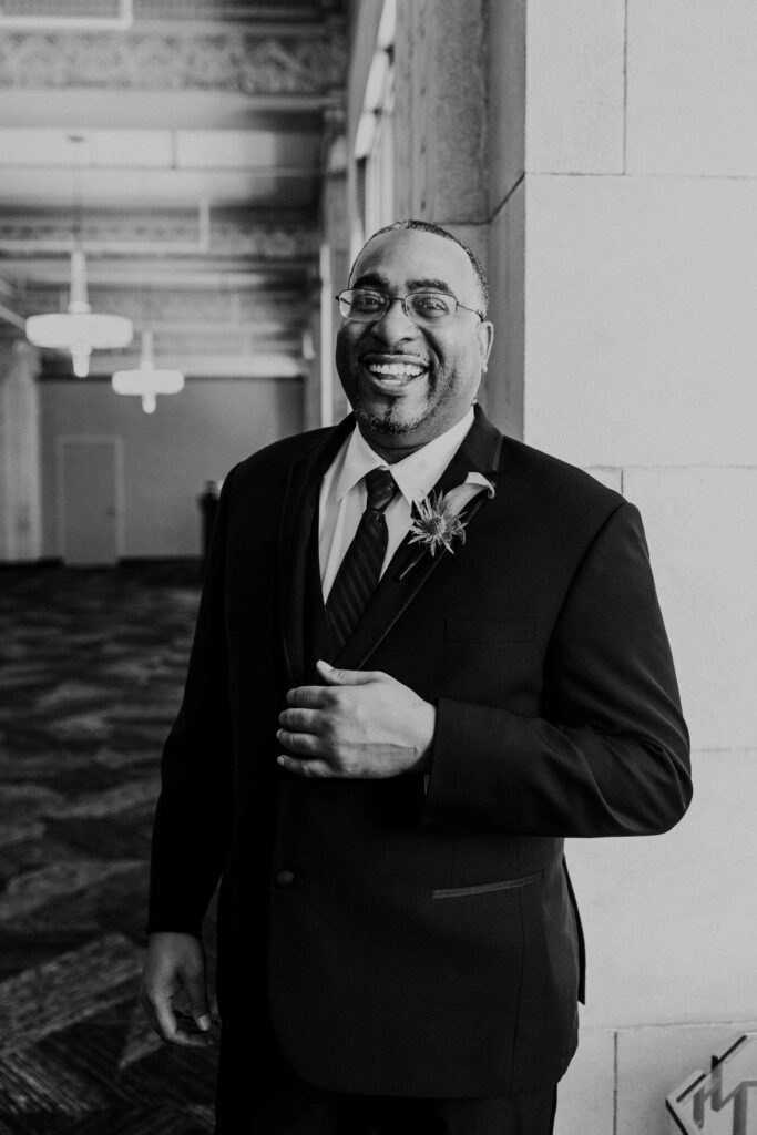 Groom smiling while dressed and ready in his wedding suit.