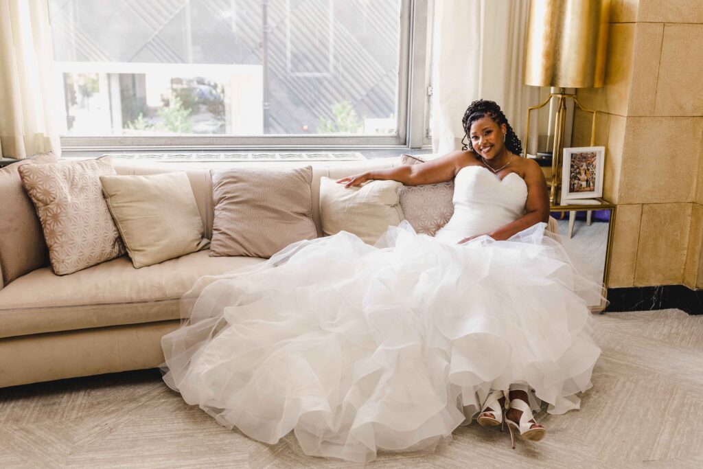 Bride smiling and sitting on a couch while waiting for her wedding ceremony at The Grand Hall at Power & Light.